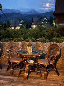 a patio table and chairs with a view of the mountains at Willa Szafran - pokoje in Zakopane