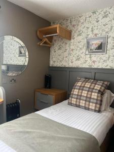 a small bedroom with a bed and a mirror at Royal Victoria Hotel Snowdonia in Llanberis