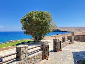 a tree in a stone wall next to the ocean at Niriides Studios & Apartments in Kithnos