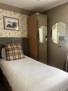 a bedroom with a bed with two mirrors on the wall at Royal Victoria Hotel Snowdonia in Llanberis