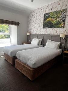 two beds in a hotel room with two beds sidx sidx sidx at Royal Victoria Hotel Snowdonia in Llanberis