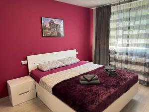 a bedroom with a bed with a red wall at West Park Apartment in Sofia