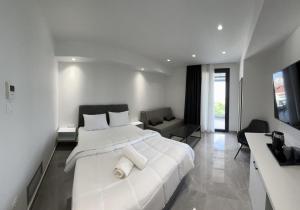 a white bedroom with a large bed and a living room at Eleva Deluxe in Kastoria
