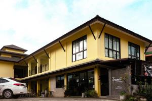 Un edificio amarillo con un coche aparcado delante. en Baan Pordeedin, en Chiang Rai
