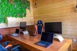 a wooden desk with three laptops and a monitor at The VALLEY, apartamentos em casa de campo nas Montanhas Mágicas - a sala e a cozinha, localizadas numa cabana de madeira, são partilhadas in Vale de Cambra
