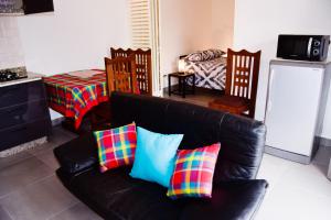 a living room with a black leather couch with colorful pillows at Résidence Créolia in Kribi