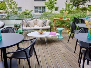 a patio with tables and chairs and a couch at Tribe Paris La Defense Esplanade in Courbevoie