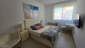 een slaapkamer met een bed, een bureau en een televisie bij SolDosMares Apartmentos in La Manga del Mar Menor +13 foto's