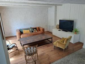 a living room with a couch and a tv at 600m bord de mer centre du val andre la maison des prés in Pléneuf-Val-André
