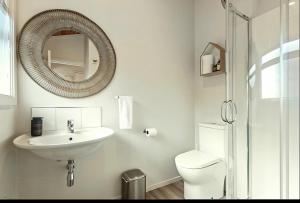 a bathroom with a sink and a toilet and a mirror at Ultimate Mount Location in Mount Maunganui