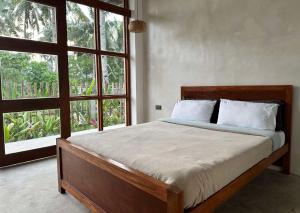 a bedroom with a bed and a large window at isla Siargao Stays in General Luna