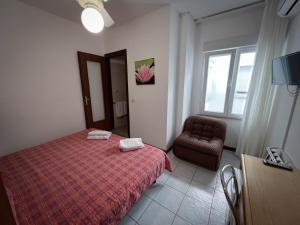 a bedroom with a bed and a chair and a window at Hotel Zen in Lignano Sabbiadoro