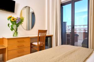 a bedroom with a desk with a mirror and a vase of flowers at Hotel Miramare in Marina di Varcaturo