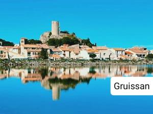 a town with a castle on top of a body of water at Entre canal et garrigue in Roubia