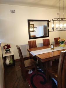 Una mesa de comedor con sillas y un espejo. en Hodson Villa, en Harare