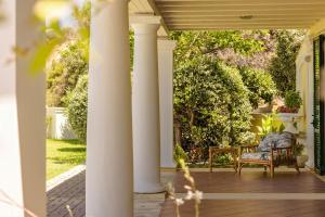 a porch with columns with a chair and a table at Villa Rhoe in Minia