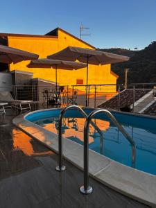 a swimming pool with tables and umbrellas next to a building at TownHouse Piraino B&B in Brolo