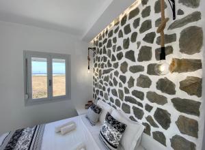 a bedroom with a stone wall and a window at Stone house Agia Anna Naxos in Agia Anna Naxos