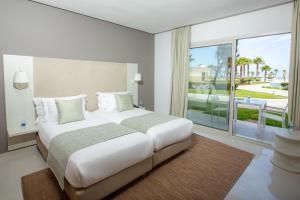 una camera da letto con un letto grande e una grande finestra di Lixus Beach Resort - All In a Larache