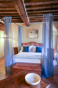 a bedroom with a bed with blue curtains and a table at Pienzalettings "Suites" in Pienza