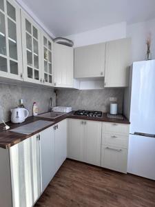 Una cocina con gabinetes blancos y un refrigerador blanco. en Apartament Ola, en Busko-Zdrój