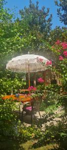 a table with an umbrella and a bench with flowers at Tuzla Garden Hotel & Spa in Tuzla