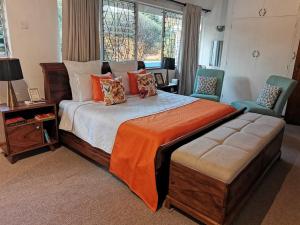Un dormitorio con una cama grande con una manta naranja en Hodson Villa, en Harare