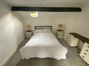a bedroom with a white bed and two night stands at Brithdir Cottage in Merthyr Tydfil