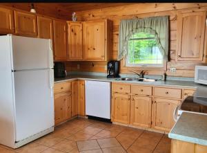 une cuisine avec des armoires en bois et un réfrigérateur blanc dans l'établissement True Living Oceanfront Cottage, à Cumberland 10 autres photos