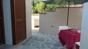 a patio with a table and an umbrella at Villa il Poderino in Marina di Campo