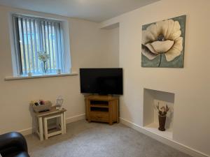 a living room with a tv and a flower painting on the wall at Brithdir Cottage in Merthyr Tydfil