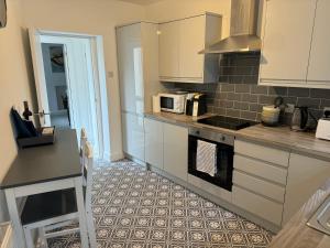 a kitchen with white cabinets and a microwave at Brithdir Cottage in Merthyr Tydfil