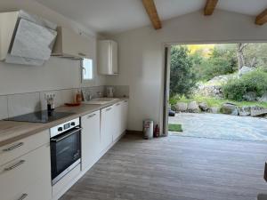 una cocina con armarios blancos y una gran puerta corredera de cristal en La campagne au bord de la mer, en Porto Vecchio