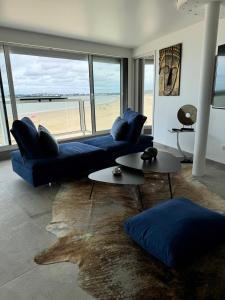 sala de estar con sofá azul y vistas a la playa en 100m2 de paradis en total vue Mer, en Saint-Georges-de-Didonne
