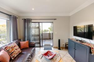 a living room with a couch and a flat screen tv at 8 On Eagle Self Catering Apartment in Umtentweni