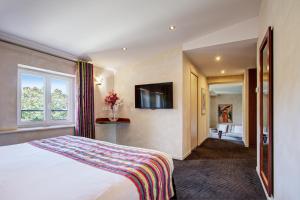 a hotel room with a bed and a television at Auberge Du Roua in Argel&egrave;s-sur-Mer