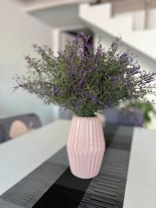 a pink vase with purple flowers sitting on a table at Urban charme loft in Dorgali
