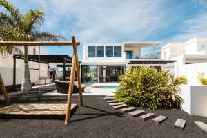 ein großes weißes Haus mit Schaukel und Spielplatz in der Unterkunft Villa María in Playa Blanca