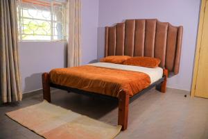 a bedroom with a bed with an orange comforter and a window at Garden Maskan Villa in Gicheru
