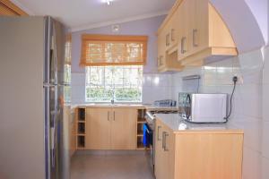 a kitchen with wooden cabinets and a white refrigerator at Garden Maskan Villa in Gicheru