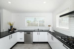 a white kitchen with white cabinets and a sink at Private room in homestay in Ashhurst