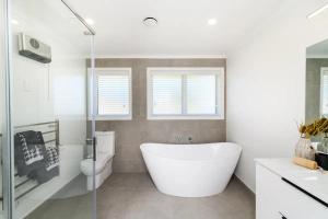 a white bathroom with a tub and a toilet at Private room in homestay in Ashhurst