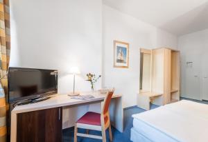 a room with a desk with a television and a bed at Pension Prenzlberg in Berlin