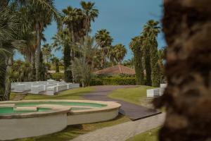 a walkway leading to a resort with palm trees at Hotel & Resort Lunatenuta in Mondragone