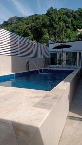 a swimming pool with an umbrella next to a house at Casa Ubatuba in Ubatuba