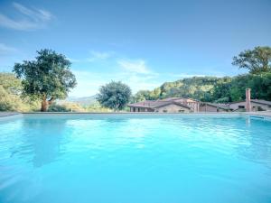 a large pool of blue water with trees in the background at Borgo Ai Cuori in Guardistallo