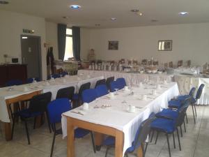 Habitación grande con mesas y sillas con mesas blancas y sillas azules. en Hotel Le Strasbourg, en Mulhouse