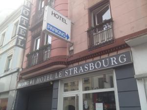 una tienda frente a un edificio con un cartel. en Hotel Le Strasbourg, en Mulhouse