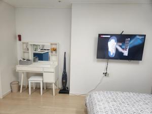 a bedroom with a desk and a tv hanging on the wall at Haeundae Bada Residence in Busan