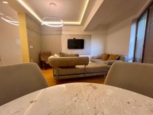 a living room with a couch and a table and chairs at Gigi Apartment by eluxory in Skopje